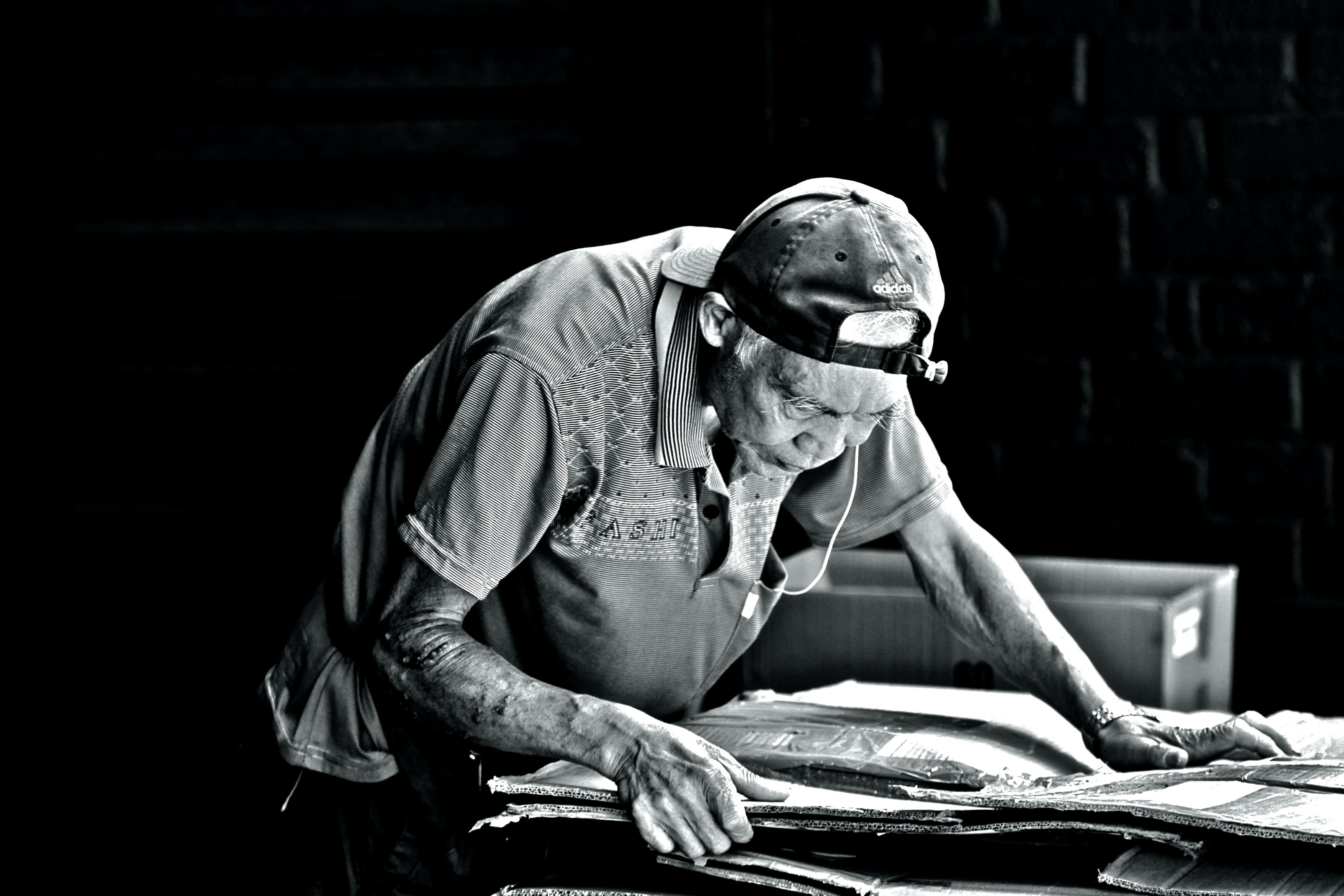 Recycler, folding corrugated for his cart. Part of the Recyclers Series #2. Tai Kok Tsui, Hong Kong 2015